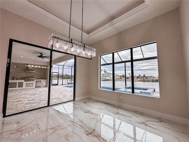 unfurnished dining area with a water view, ceiling fan, ornamental molding, and a raised ceiling