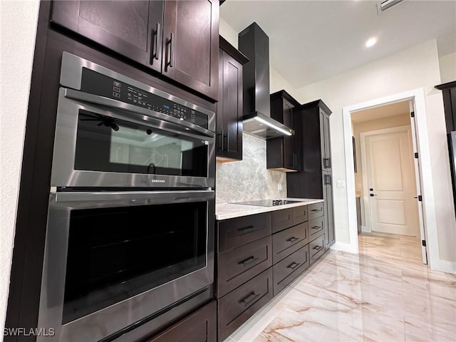 kitchen featuring double oven, dark brown cabinets, tasteful backsplash, black electric cooktop, and wall chimney exhaust hood