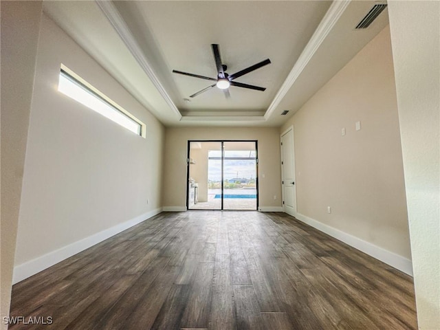 empty room featuring ceiling fan, crown molding, dark hardwood / wood-style flooring, and a tray ceiling