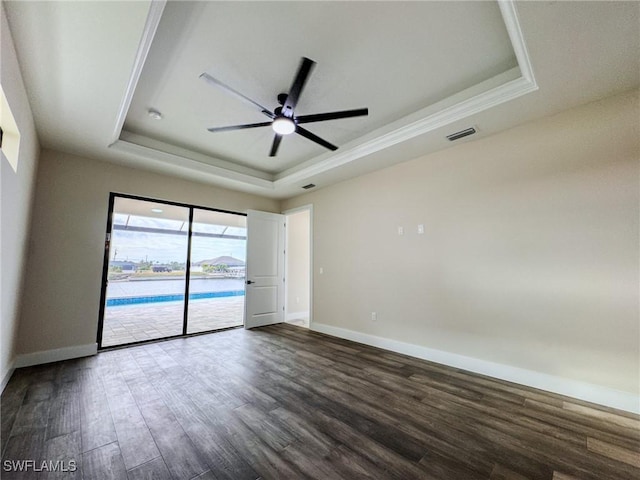 spare room featuring dark wood-type flooring, a raised ceiling, and ceiling fan