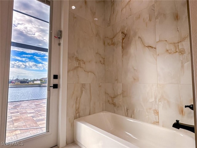 bathroom featuring a tub to relax in and a water view