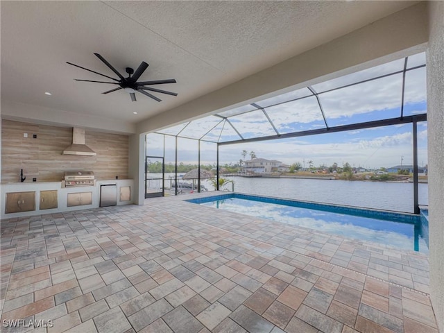 view of pool with an outdoor kitchen, a lanai, grilling area, a water view, and a patio area