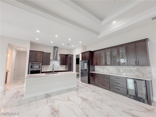 kitchen with appliances with stainless steel finishes, sink, backsplash, dark brown cabinetry, and wall chimney exhaust hood