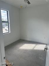 spare room featuring plenty of natural light, concrete flooring, and ceiling fan