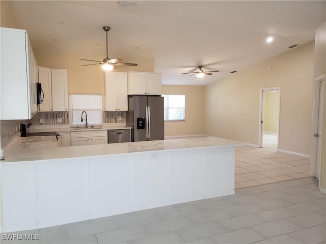 kitchen featuring appliances with stainless steel finishes, sink, white cabinets, decorative backsplash, and kitchen peninsula