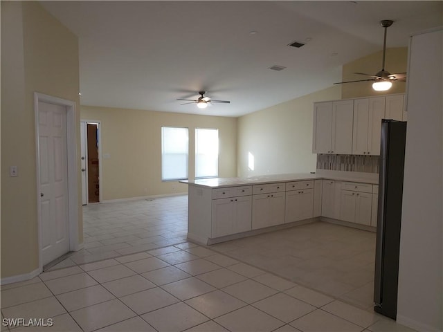 kitchen featuring light tile patterned floors, ceiling fan, black refrigerator, white cabinets, and kitchen peninsula