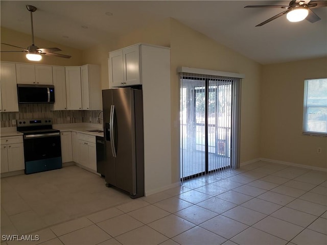 kitchen with vaulted ceiling, appliances with stainless steel finishes, tasteful backsplash, white cabinets, and light tile patterned floors