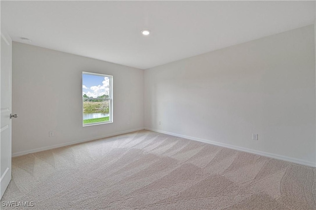 carpeted spare room featuring a water view