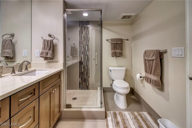 bathroom featuring tile patterned flooring, vanity, a shower with shower door, and toilet