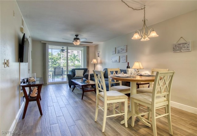 dining area with hardwood / wood-style floors and ceiling fan with notable chandelier