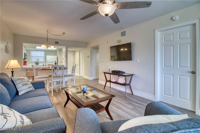 living room featuring ceiling fan with notable chandelier and light hardwood / wood-style floors