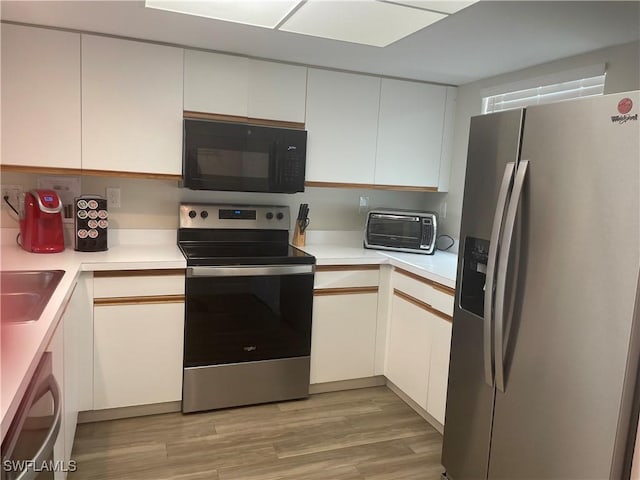 kitchen featuring white cabinetry, appliances with stainless steel finishes, sink, and light wood-type flooring