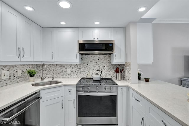 kitchen with stainless steel appliances, tasteful backsplash, sink, and white cabinets