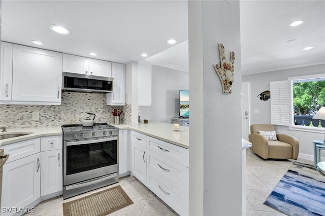 kitchen with light tile patterned flooring, white cabinetry, ornamental molding, appliances with stainless steel finishes, and backsplash