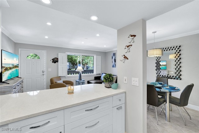 kitchen featuring crown molding, light tile patterned floors, decorative light fixtures, and white cabinets