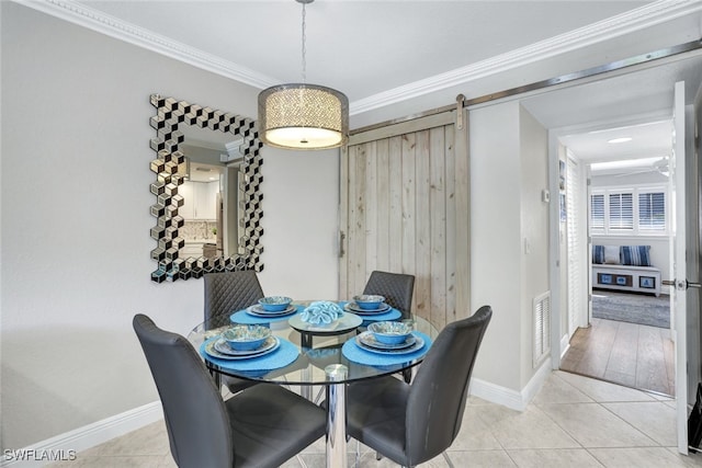 dining area featuring light tile patterned floors, crown molding, and a barn door