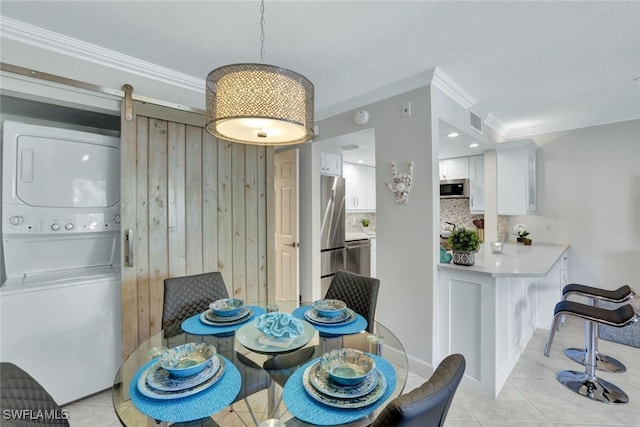 dining room featuring crown molding, stacked washer and dryer, wood walls, and light tile patterned floors