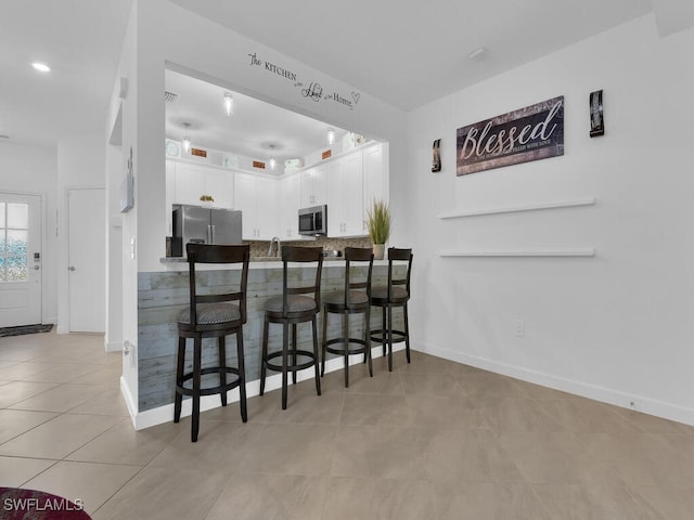 bar featuring white cabinetry, light tile patterned flooring, and appliances with stainless steel finishes