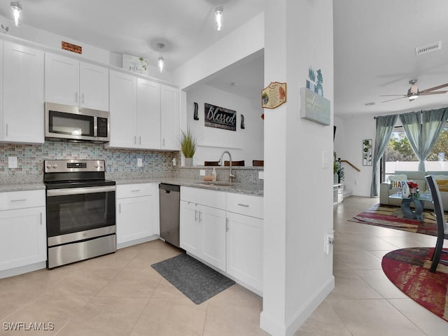 kitchen featuring sink, white cabinets, light tile patterned floors, stainless steel appliances, and light stone countertops