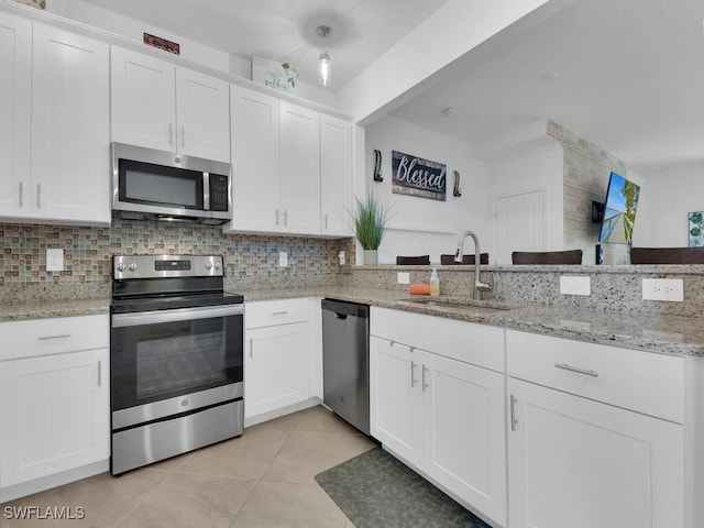 kitchen featuring sink, light tile patterned floors, white cabinets, stainless steel appliances, and backsplash