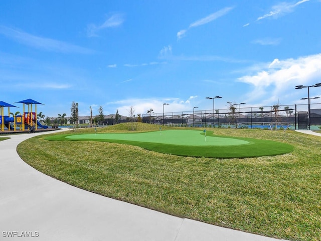 view of home's community with a playground, a lawn, and tennis court