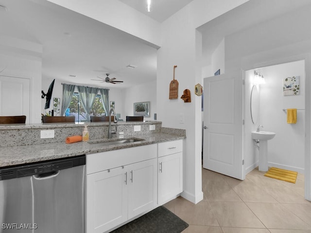 kitchen with dishwasher, sink, white cabinets, light tile patterned floors, and light stone counters