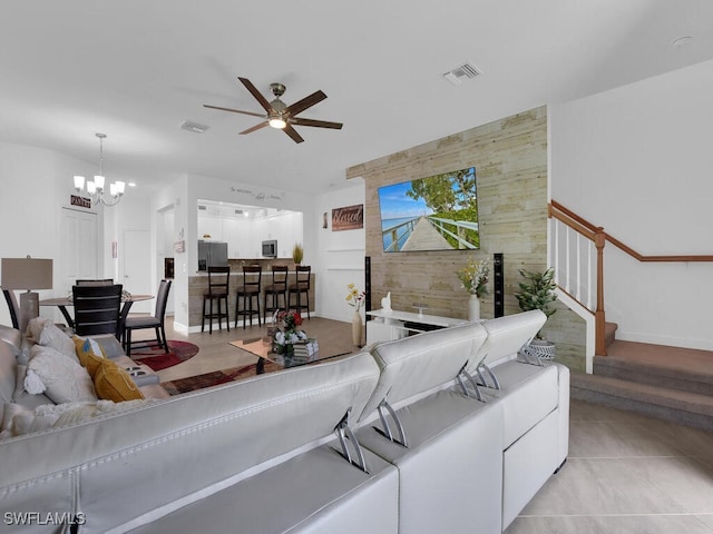 living room with light tile patterned floors and ceiling fan with notable chandelier