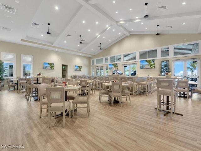 dining space featuring high vaulted ceiling, light hardwood / wood-style floors, and beamed ceiling