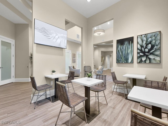 dining space featuring a towering ceiling and light wood-type flooring