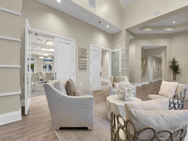 living room with a towering ceiling and light hardwood / wood-style flooring