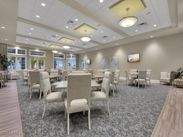 dining space featuring wood-type flooring, a raised ceiling, and a drop ceiling