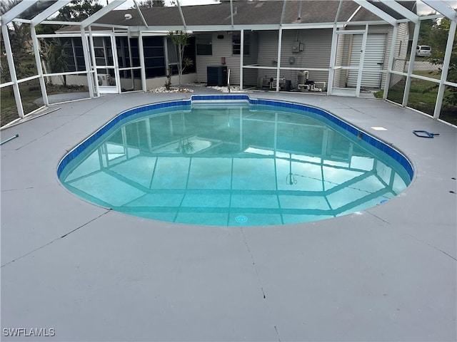 view of pool with cooling unit, a lanai, and a patio area