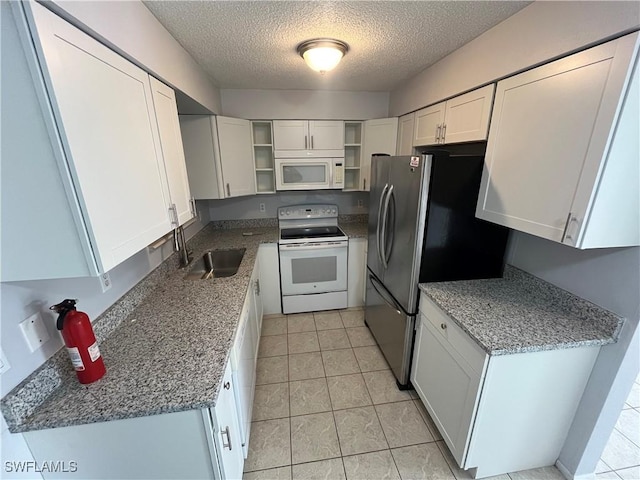 kitchen with stone countertops, sink, white cabinets, white appliances, and a textured ceiling