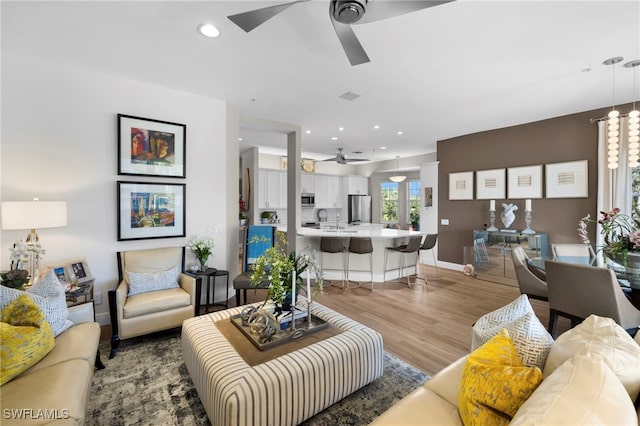 living room featuring ceiling fan and light hardwood / wood-style floors