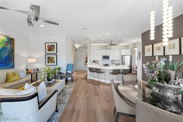 living room with light hardwood / wood-style flooring and ceiling fan