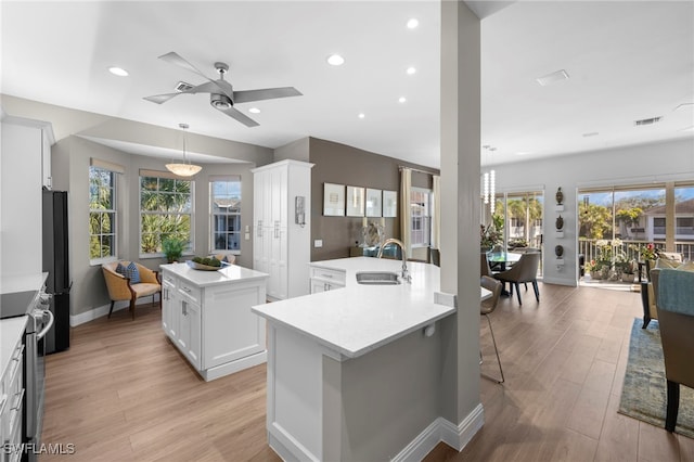 kitchen with sink, white cabinetry, light hardwood / wood-style flooring, electric stove, and a kitchen island with sink