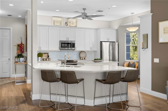 kitchen featuring sink, a kitchen breakfast bar, stainless steel appliances, decorative backsplash, and white cabinets