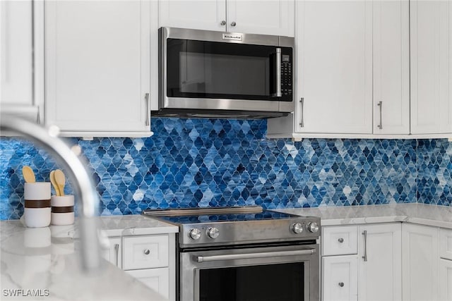 kitchen featuring white cabinetry, decorative backsplash, and stainless steel appliances