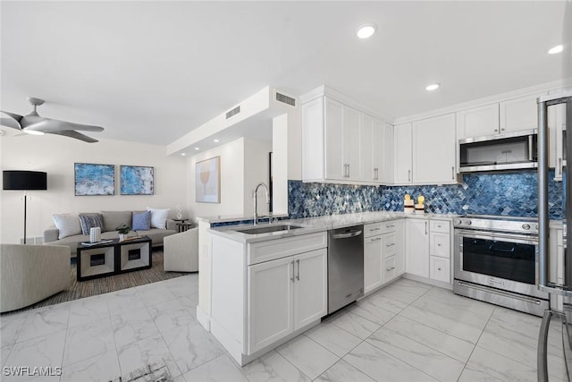 kitchen with sink, appliances with stainless steel finishes, white cabinets, decorative backsplash, and kitchen peninsula