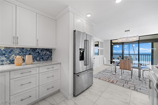 kitchen featuring a water view, white cabinetry, hanging light fixtures, high quality fridge, and decorative backsplash