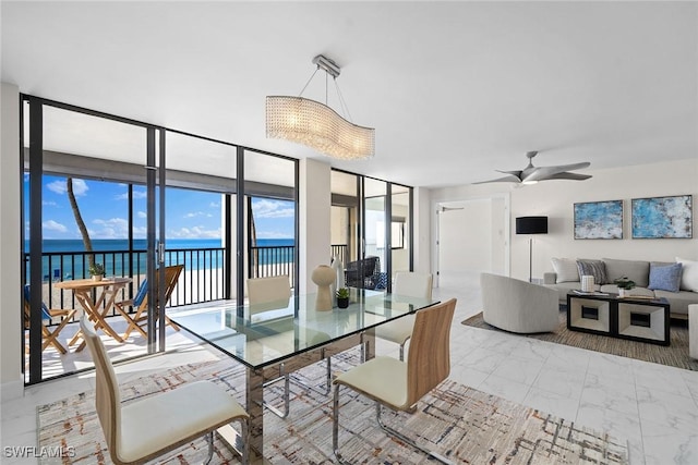 dining space featuring a wall of windows, ceiling fan, and a water view