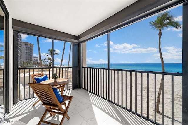 sunroom with a water view, a healthy amount of sunlight, and a beach view