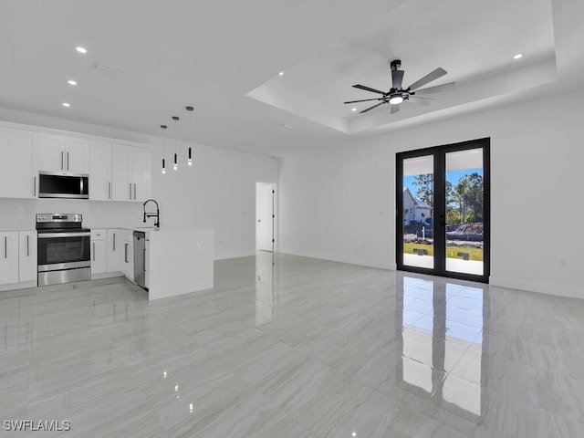 unfurnished living room with french doors, ceiling fan, a raised ceiling, and sink