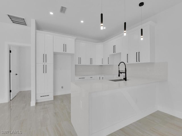 kitchen with sink, white cabinetry, backsplash, decorative light fixtures, and kitchen peninsula