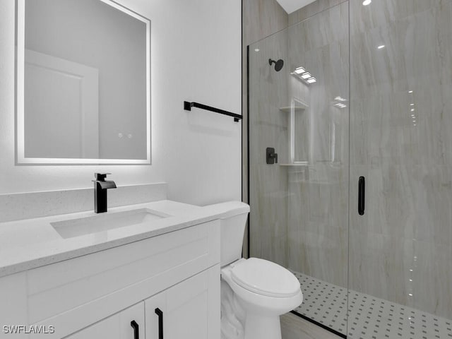 bathroom featuring vanity, an enclosed shower, and toilet