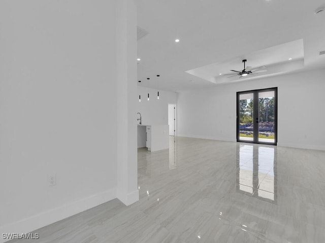 unfurnished room featuring sink, a raised ceiling, ceiling fan, and french doors