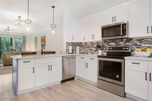 kitchen featuring sink, appliances with stainless steel finishes, white cabinetry, hanging light fixtures, and kitchen peninsula