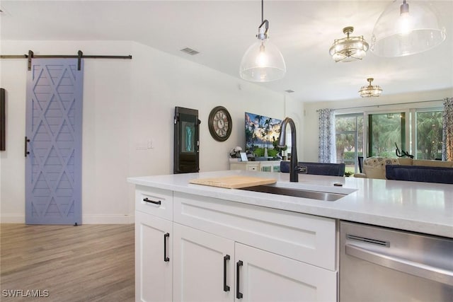 kitchen with decorative light fixtures, dishwasher, a barn door, light hardwood / wood-style floors, and white cabinets