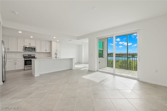 unfurnished living room with a water view, sink, and light tile patterned floors