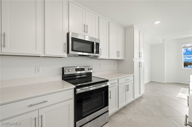 kitchen with appliances with stainless steel finishes, light tile patterned floors, and white cabinets